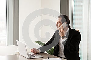 Serious young businessman in office making phone call.