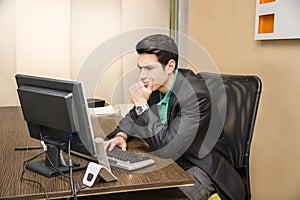 Serious young businessman sitting at desk in office
