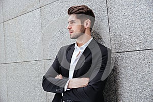 Serious young businessman standing with arms crossed