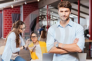 Serious young businessman standing with arms crossed