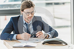 serious young businessman with various documents on table looking
