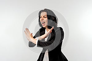 Serious young businesswoman in black formal jacket white shirt shows cross stop gesture with an angry aggressive expression,