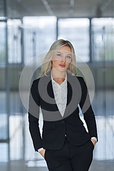 Serious young businesswoman with hands in pockets looking at camera