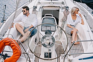 serious young couple in sunglasses looking away while sitting