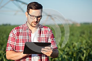 Serious young farmer working on a tablet in corn field
