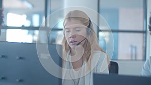 Serious young female operator in headset talking to customer