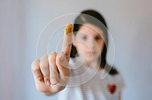 Serious young girl looking at camera while showing her finger covered of golden glitter