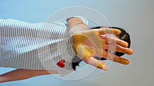 Serious young girl showing her palm hand covered of golden glitter while doing stop sign