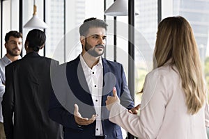 Serious young Indian businessman talking to Caucasian female colleague