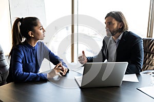 Serious young male boss talking to female employee.