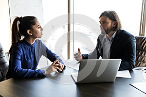 Serious young male boss talking to female employee. photo