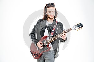 Serious young male guitarist standing and playing electric guitar