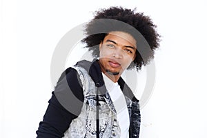 Serious young man with afro standing against white wall