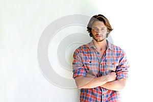 Serious young man with arms crossed on white background