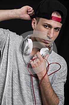 Serious young man in a cap and with headphones around his neck