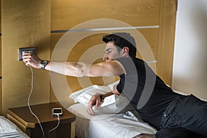 Serious Young Man Connecting a Phone to a Charger