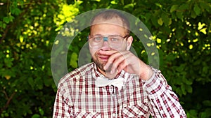 Serious young man in glasses staring into the camera and rubbing