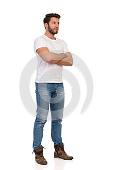 Serious Young Man In Jeans And White T-shirt Is Standing With Arms Crossed