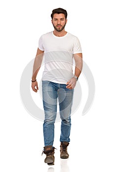 Serious Young Man In Jeans And White T-shirt Is Walking Towards Camera