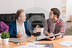 Serious young man listening to his senior colleague