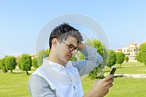 Serious young man outdoor with mobile phone.