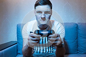 Serious young man playing a video game at home