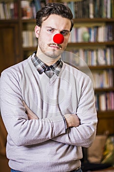 Serious young man with red clown nose