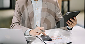 Serious young man sit at workplace desk in office use calculator calculates monthly expenses, taxes, personal budget management photo