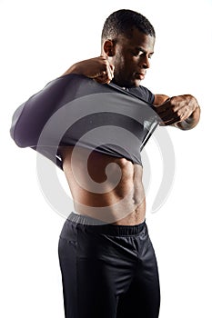 Serious young man takes off his black t-shirt, isolated on white