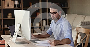 Serious young man work from home office using two computers