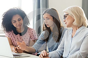 Serious young and old businesswomen working together focused on computer