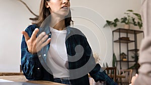 Serious young professional woman in informal clothes talking to colleague