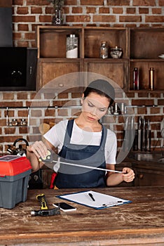 serious young repairwoman with measuring tape and clipboard