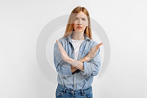 Serious young woman, arms crossed, showing stop gesture, on white background