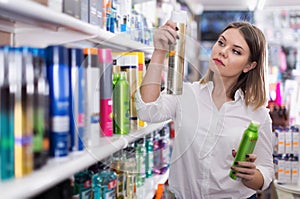 Serious young woman choosing hair care products