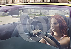 Serious young woman driving away from house