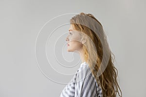 Serious young woman with long wavy red hair side view