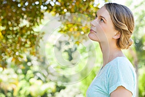 Serious young woman looking at leaves in park