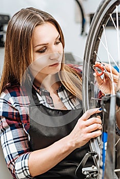 Serious young woman pumping the wheel of the bicycle