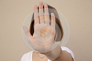 Serious young woman showing stop hand sign, on isolated background