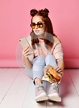 Serious young woman in trendy eyewear concentrated on information looking at phone