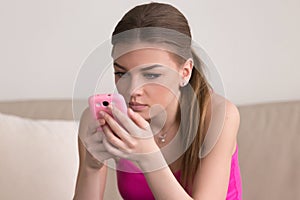 Serious young woman using cellphone at home