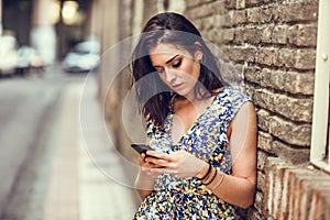 Serious young woman using her smart phone outdoors.