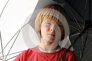Seriouse boy with umbrellas