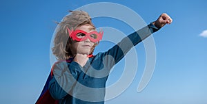 Seriuos child wearing a superhero costume. Super hero child against blue summer sky background. Kid having fun outdoors