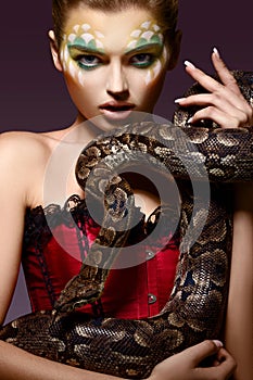 Serpent. Fantasy. Fancy Woman holding Tamed Snake in Hands photo