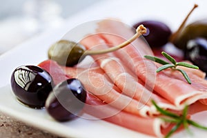 Serrano ham with olives and caper berries photo