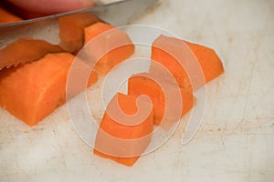 Serrated metal knife cuts orange carrots