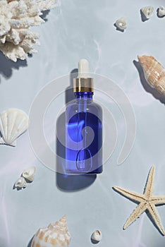 Serum blue bottle with sea shells islolated on light background