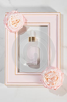 Serum bottle with dropper with rose flowers on marble background. Aromatherapy oil. natural beauty product for skin or